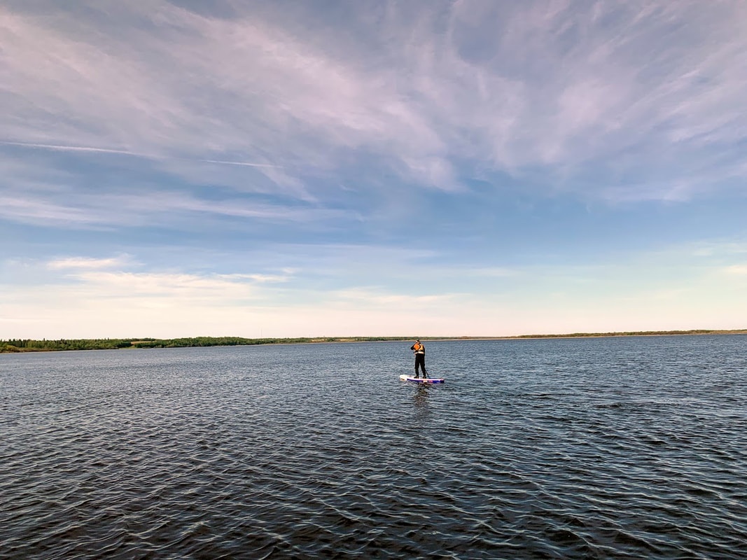 SUP paddler on a rippled lake under an open sky