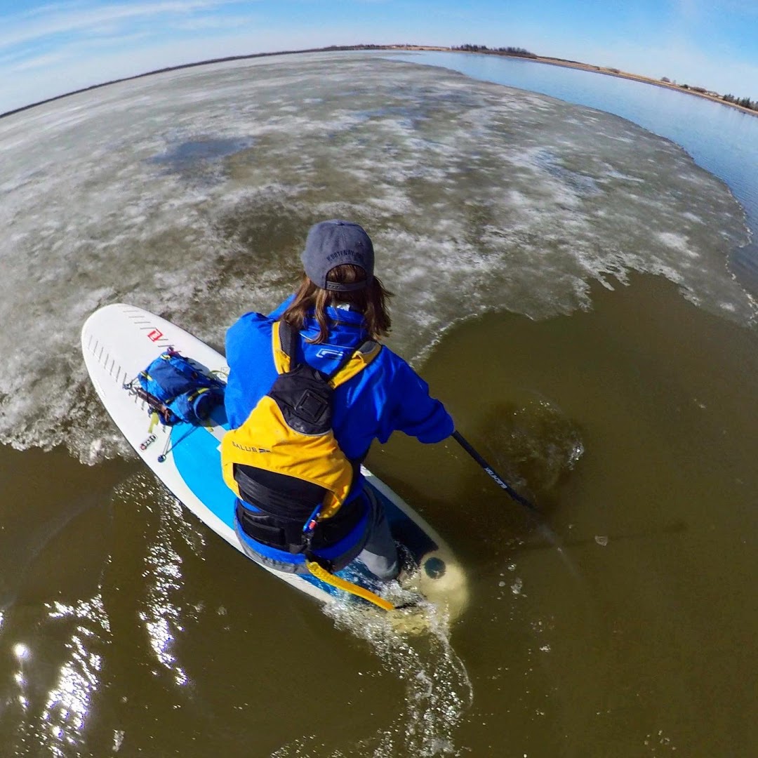 SUP paddler completing pivot turn with nose over lake ice